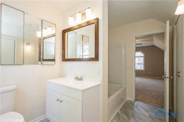 full bath featuring vanity, toilet, baseboards, a bathing tub, and vaulted ceiling