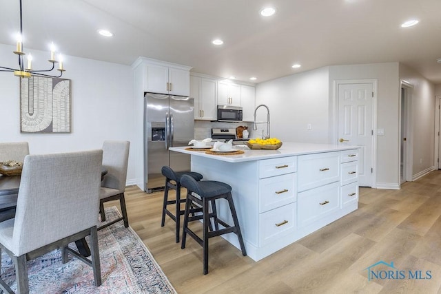 26328 Stillwater Dr, Perrysburg, OH 43551 - kitchen featuring appliances with stainless steel finishes, light wood-type flooring, white cabinetry, tasteful backsplash, and light countertops