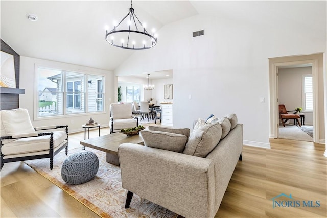 26328 Stillwater Dr, Perrysburg, OH 43551 - living room featuring a chandelier, healthy amount of natural light, light wood-style flooring, high vaulted ceiling, and baseboards