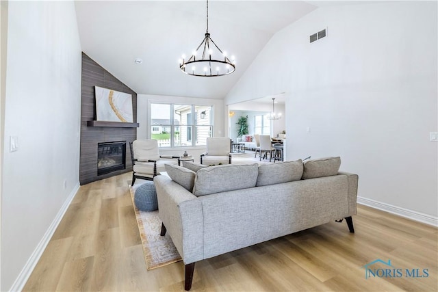 26328 Stillwater Dr, Perrysburg, OH 43551 - living room with a chandelier, a glass covered fireplace, light wood-style floors, baseboards, and high vaulted ceiling