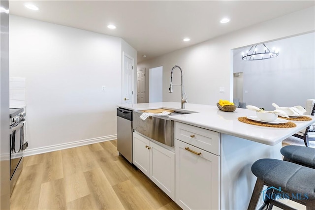 26328 Stillwater Dr, Perrysburg, OH 43551 - kitchen featuring stainless steel dishwasher, a sink, a breakfast bar, white cabinetry, and light countertops