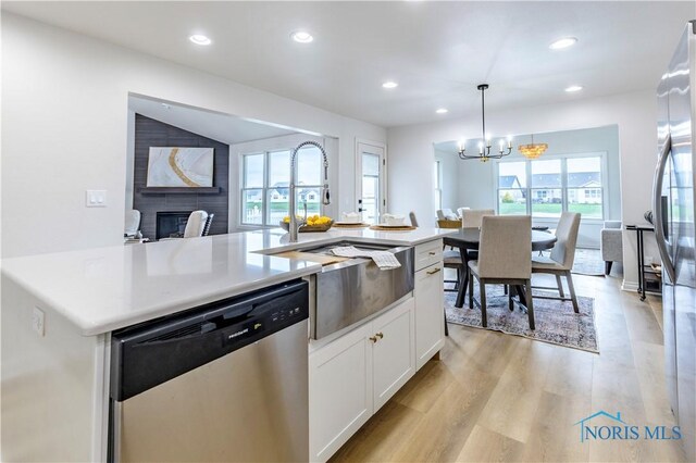 26328 Stillwater Dr, Perrysburg, OH 43551 - kitchen with appliances with stainless steel finishes, a sink, a glass covered fireplace, a chandelier, and white cabinetry