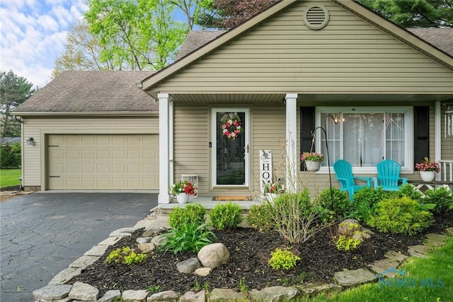 view of front of home with a garage, roof with shingles, a porch, and driveway