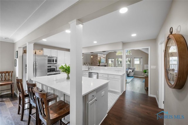 kitchen featuring a sink, light countertops, a kitchen breakfast bar, a center island, and stainless steel appliances