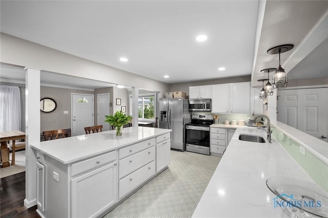 kitchen with white cabinets, light stone countertops, a sink, stainless steel appliances, and recessed lighting