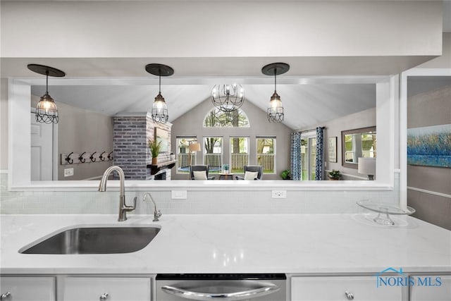 kitchen featuring stainless steel dishwasher, white cabinetry, vaulted ceiling, and a sink