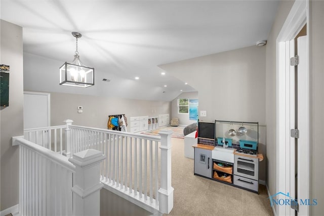 interior space with carpet floors, an upstairs landing, an inviting chandelier, and vaulted ceiling