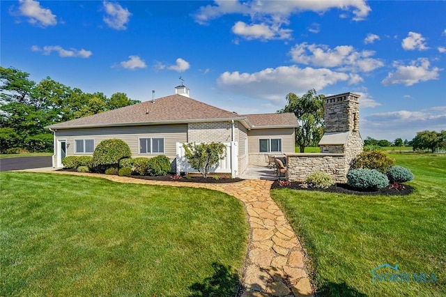 view of front of property with a chimney, a shingled roof, and a front yard