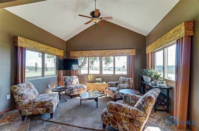 living room featuring ceiling fan, lofted ceiling, a healthy amount of sunlight, and stone finish floor
