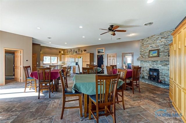 dining area with ceiling fan, a wood stove, recessed lighting, stone finish flooring, and visible vents