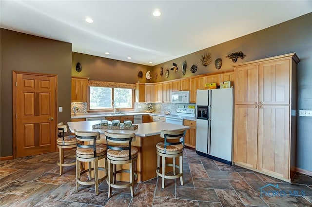 kitchen with a center island, light countertops, decorative backsplash, and white appliances