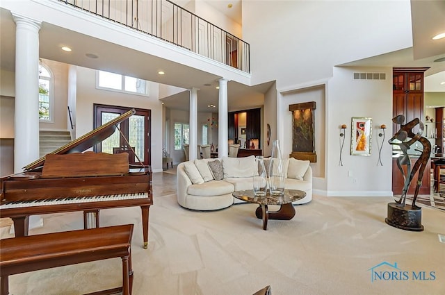living room featuring visible vents, baseboards, ornate columns, and carpet floors