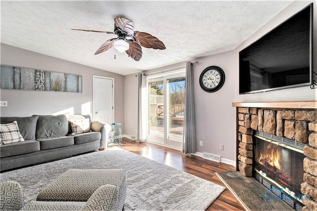 29058 White Rd, Perrysburg, OH 43551 - living room with ceiling fan, a stone fireplace, baseboards, wood finished floors, and visible vents