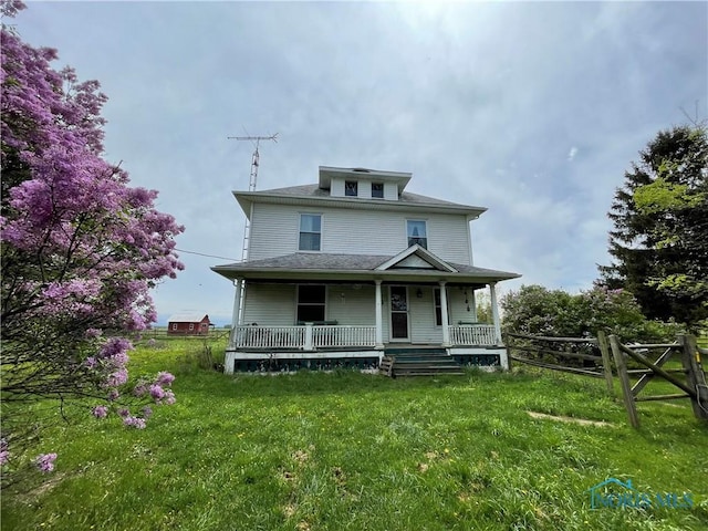 american foursquare style home featuring fence, covered porch, and a front lawn