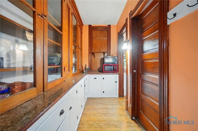 13707 Brint Rd, Berkey, OH 43504 - kitchen featuring light wood-style floors, white cabinets, dark stone counters, and glass insert cabinets