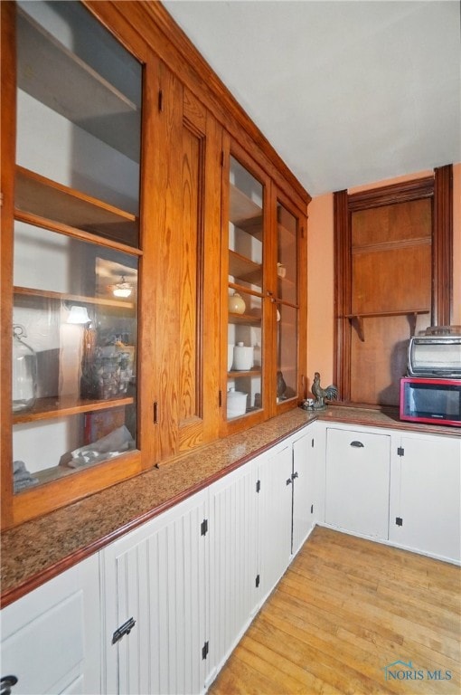 13707 Brint Rd, Berkey, OH 43504 - kitchen with light wood finished floors, glass insert cabinets, and white cabinetry