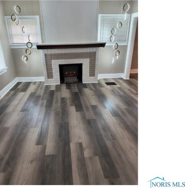 unfurnished living room featuring baseboards, dark wood finished floors, visible vents, and a fireplace