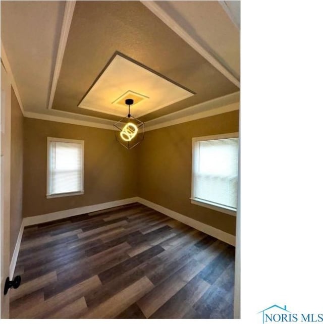 unfurnished room featuring dark wood-style flooring, baseboards, ornamental molding, and a raised ceiling