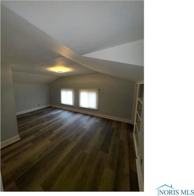 additional living space with baseboards, wood finished floors, and lofted ceiling