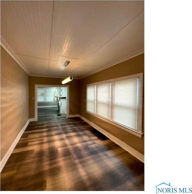 unfurnished dining area with baseboards, ornamental molding, and dark wood finished floors