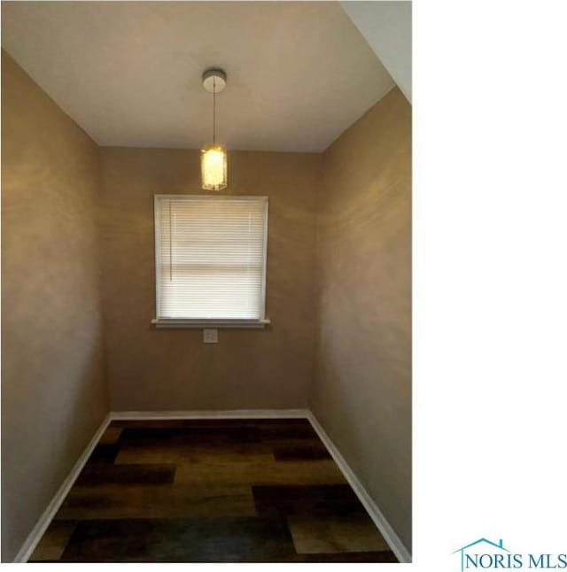 unfurnished dining area with baseboards and dark wood finished floors