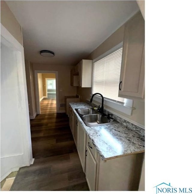 kitchen featuring light countertops, dark wood-style flooring, baseboards, and a sink