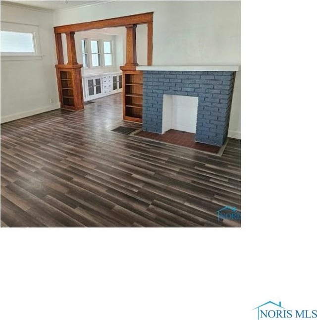 unfurnished living room with a fireplace, french doors, ornamental molding, baseboards, and dark wood-style floors