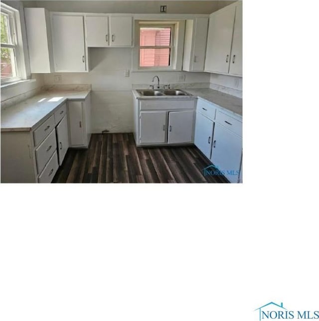 kitchen with a sink, light countertops, white cabinets, and dark wood-style flooring