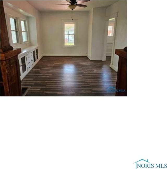 interior space with baseboards, a ceiling fan, and dark wood finished floors