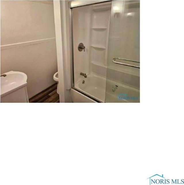 bathroom with toilet and shower / bath combination with glass door