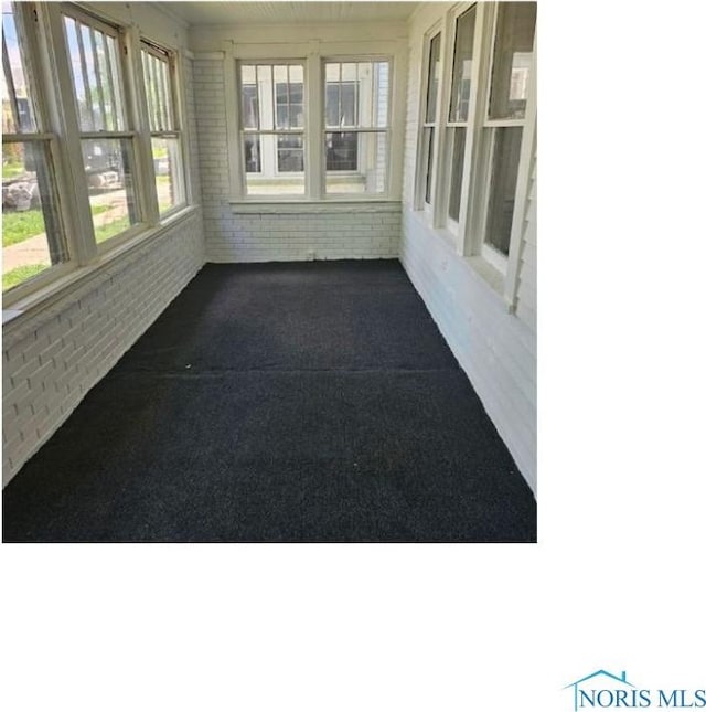 unfurnished sunroom featuring brick wall