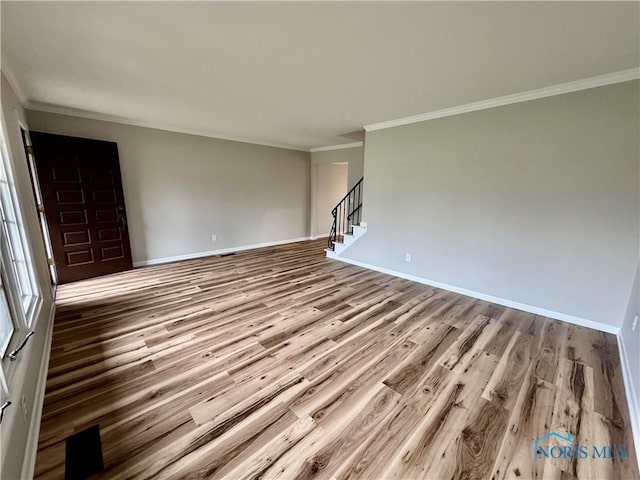 unfurnished living room featuring crown molding, baseboards, and wood finished floors