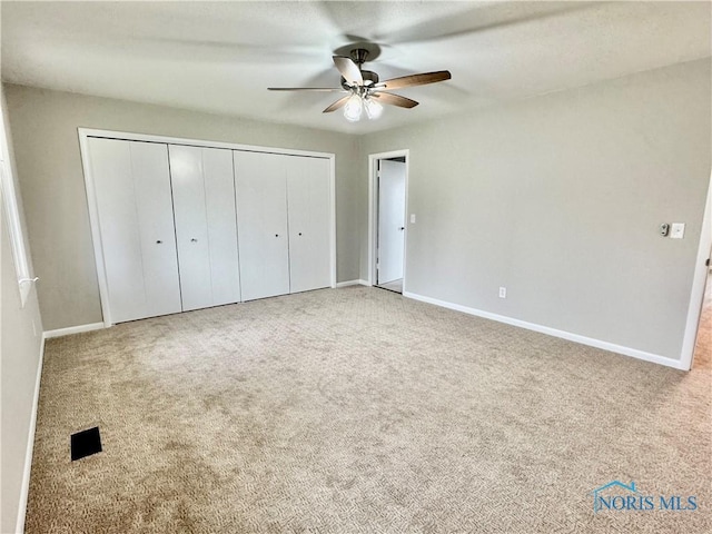 unfurnished bedroom featuring a closet, baseboards, ceiling fan, and carpet flooring