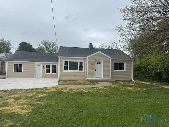 view of front of property with roof with shingles, a front yard, a chimney, and a patio area