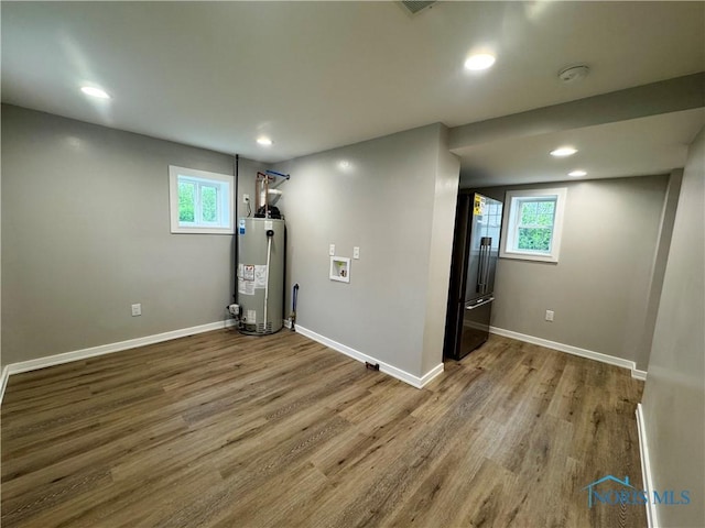below grade area featuring plenty of natural light, high quality fridge, water heater, and wood finished floors
