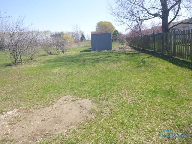 view of yard featuring fence, an outbuilding, and a shed