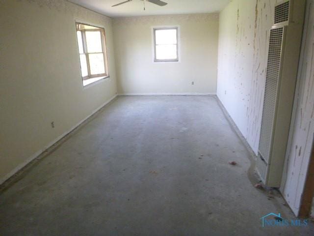 unfurnished room featuring a heating unit, unfinished concrete flooring, and ceiling fan