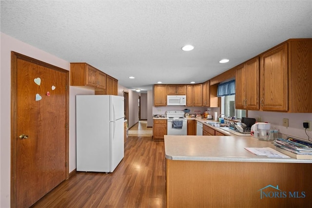 5788 Emerson Rd, Bloomdale, OH 44817 - kitchen with white appliances, wood finished floors, a peninsula, brown cabinets, and recessed lighting