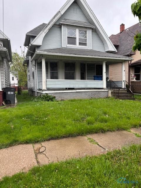 view of front of home featuring a shingled roof, a front lawn, and covered porch