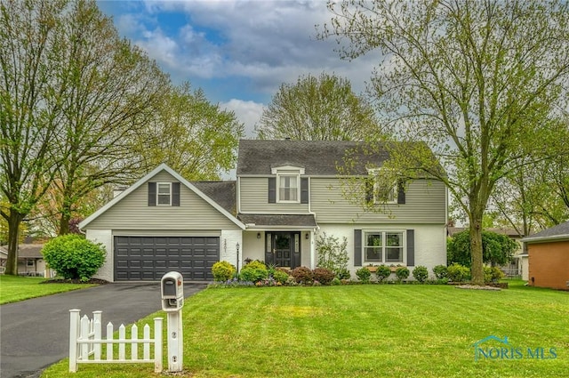 traditional-style house featuring fence, a shingled roof, an attached garage, a front lawn, and driveway