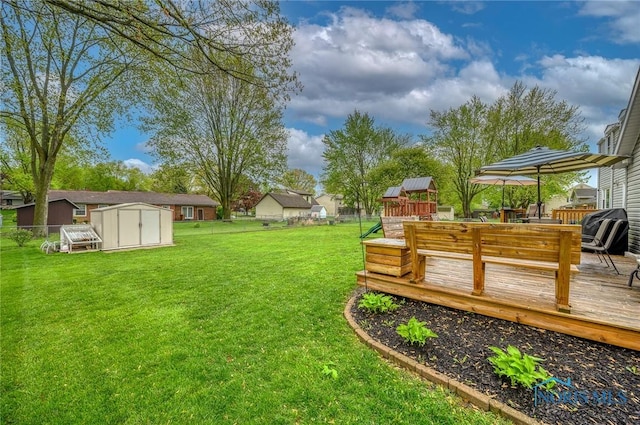 view of yard featuring a deck, fence, an outbuilding, and a shed