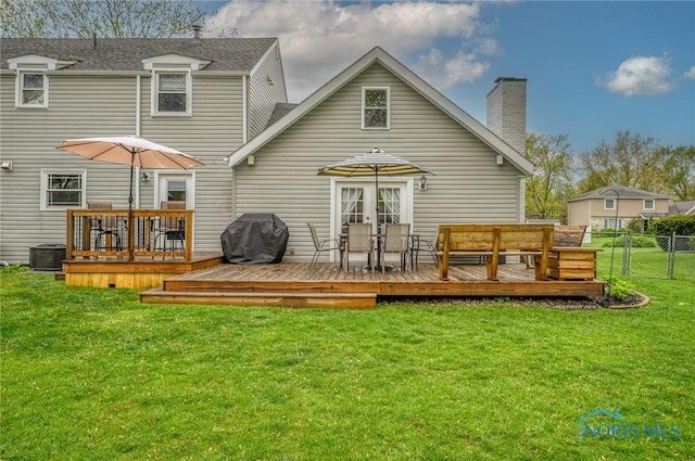back of property with fence, a deck, a chimney, central air condition unit, and a yard