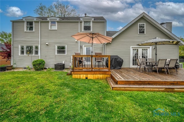 rear view of house featuring central AC, a deck, outdoor dining area, french doors, and a yard