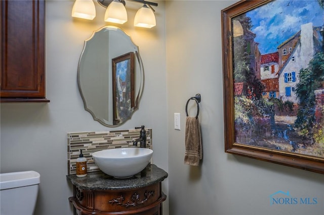 bathroom with toilet, decorative backsplash, and vanity