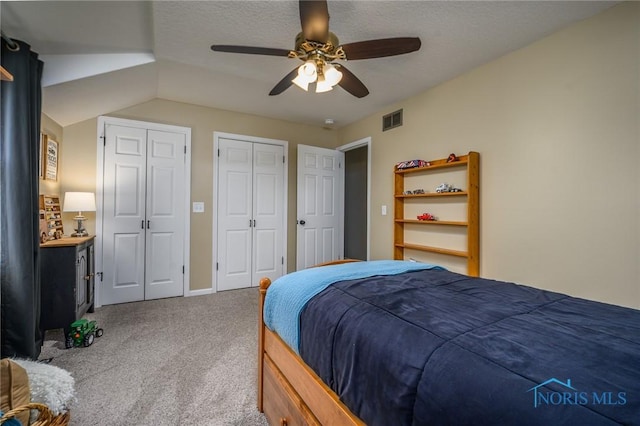 bedroom with a ceiling fan, carpet flooring, two closets, and visible vents