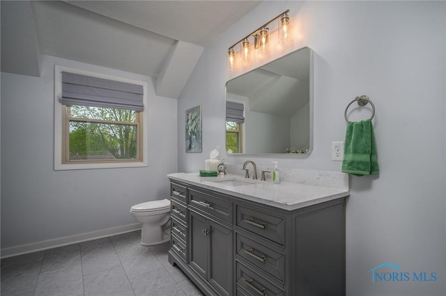 bathroom featuring baseboards, a wealth of natural light, toilet, and vanity