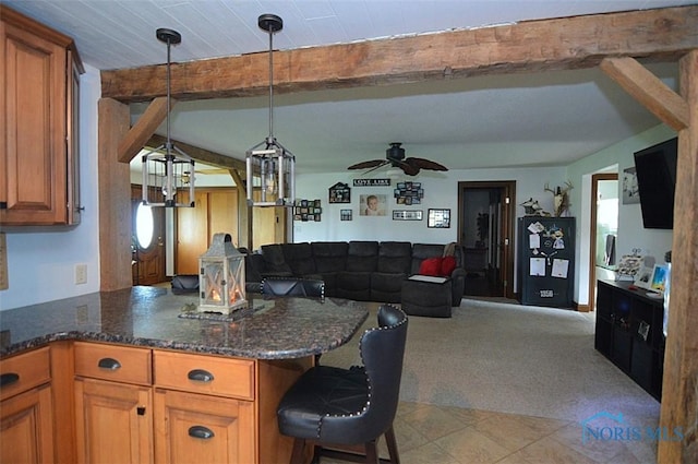 kitchen with beamed ceiling, ceiling fan, brown cabinetry, and open floor plan