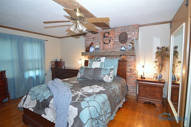 bedroom with a textured ceiling, ornamental molding, and wood finished floors