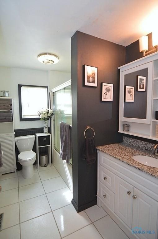 full bath featuring toilet, tile patterned floors, combined bath / shower with glass door, and vanity