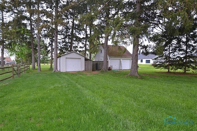 view of yard featuring a detached garage, fence, and an outdoor structure